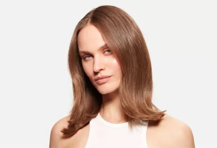 Portrat einer Frau mit mittellangen, glanzenden und gut gestylten braunen Haaren vor weißem Hintergrund.