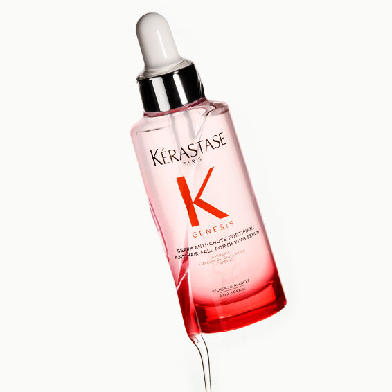 Frau in rotem Top mit dunklem, glattem Haar, zur Veranschaulichung der Wirksamkeit des Kerastase Anti-Haarausfall-Serums