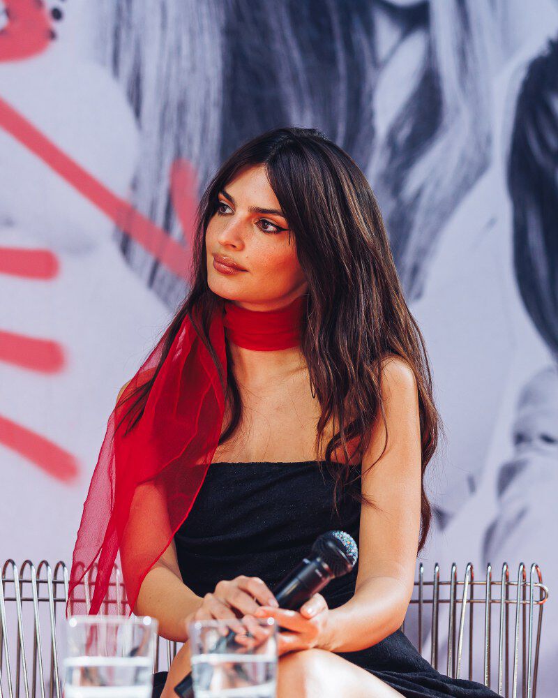 Emily Ratajkowski, Kerastase-Gesicht, in einer farbenfrohen Kulisse: blau und rot – aufmerksam der Diskussion folgend