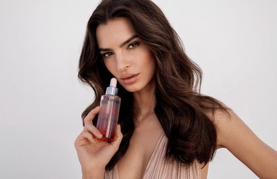 Kerastase-Serumflasche neben einer roten Rose, zur Veranschaulichung der Verankerung und Fixierung des Haares an der Wurzel