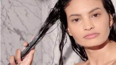 Auftragen von Conditioner auf lockige Haarstrahnen zum Entwirren und Feuchtigkeitsspenden der Haarfaser