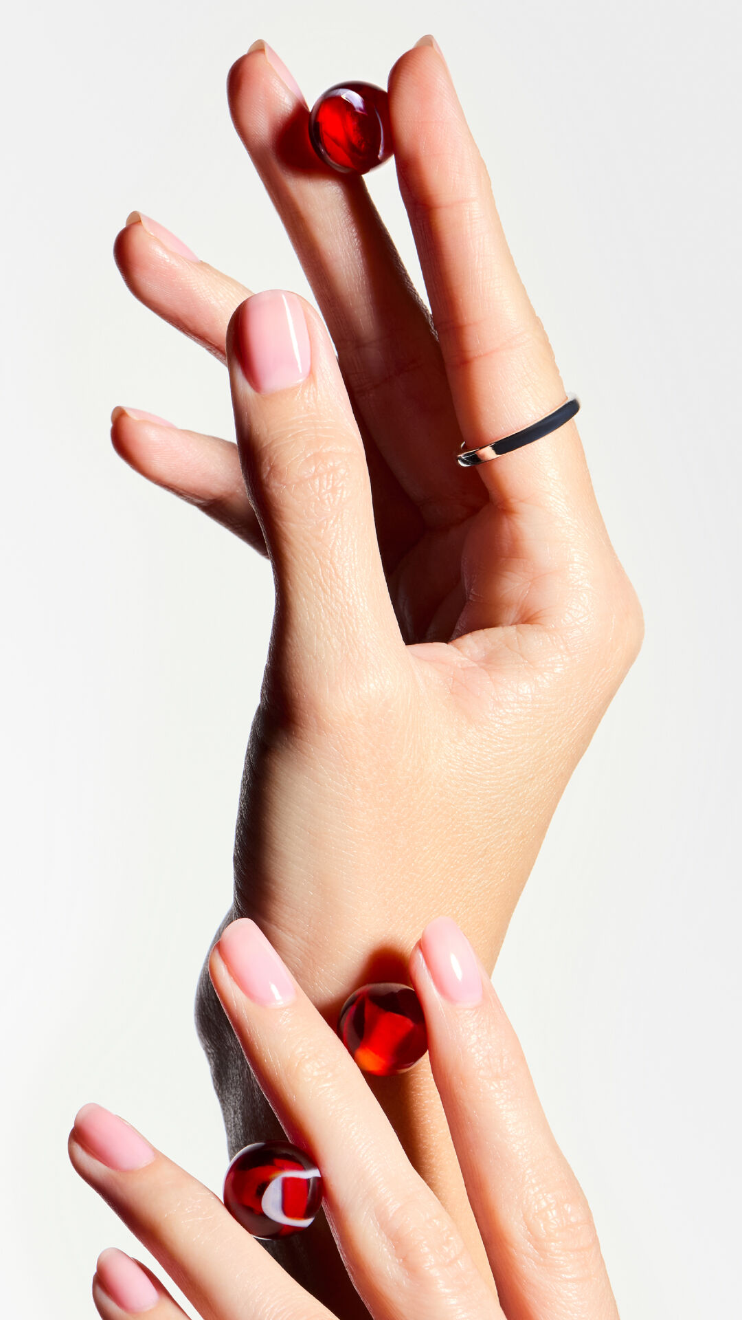 Nahaufnahme von Handen mit rotem Nagellack, die ein Anti-Haarausfall-Pflegeprodukt halten