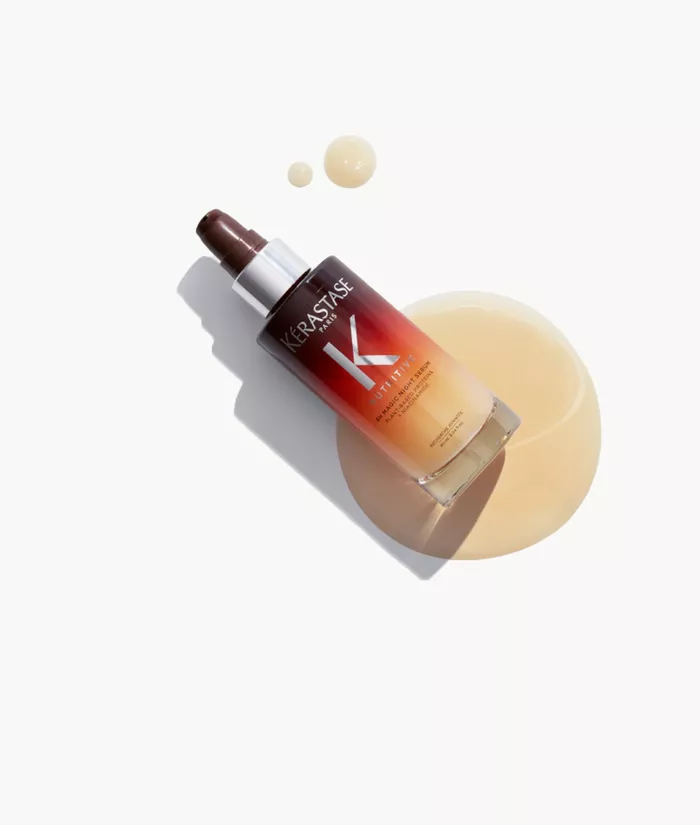 Eine Flasche Haarpflegeprodukt von Kerastase mit einem Gradient-Design, umgeben von einem Tropfen des Produkts auf einem hellen Hintergrund.