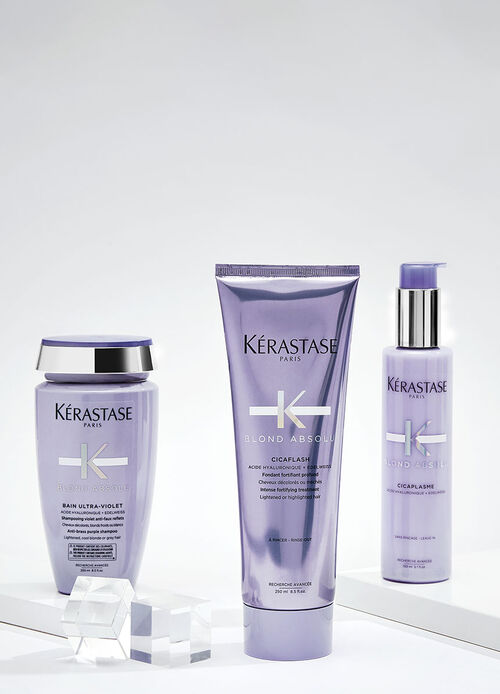 Eine Gruppe von Haarpflegeprodukten der Marke Kerastase, einschließlich Shampoos, Seren und Masken, vor einem violetten Hintergrund.