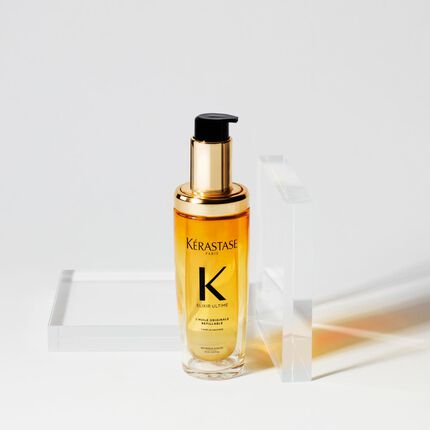 Ein Flakon mit Kerastase Elixir Ultime Haarserum, umgeben von transparenten geometrischen Formen auf einem weißen Hintergrund.