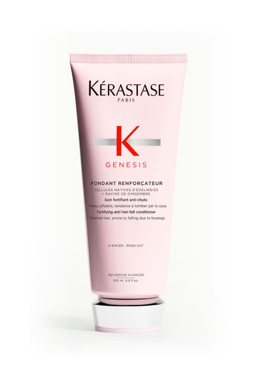 Hande halten eine rosa Tube des Kerastase Genesis Fondant Renforcateur Conditioners.