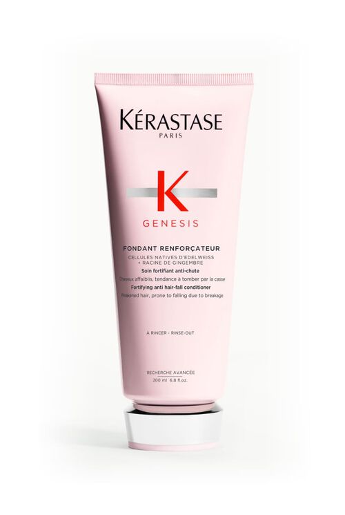 Hande halten eine rosa Tube des Kerastase Genesis Fondant Renforcateur Conditioners.