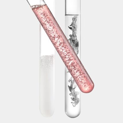 Ein Reagenzglas mit roser Flussigkeit, gefullt mit Blasen, steht neben einem transparenten Behalter mit klarer Flussigkeit.