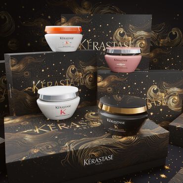 Four stylish hair care jars from Kerastase are displayed on a shimmering, decorative background featuring swirling golden designs and dark packaging.