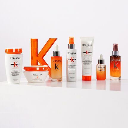 A display of hair care products from the brand Kerastase, featuring various bottles and jars on a white background, with a prominent orange "K" logo.