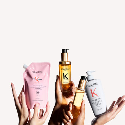 Eine Gruppe von Handen halt verschiedene Produkte von Kerastase, darunter Shampoo, Haarol und Conditioner, auf einem neutralen Hintergrund.
