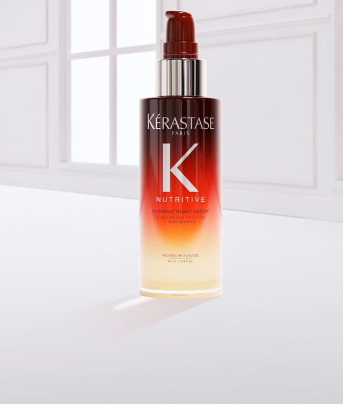 Eine Flasche Haarpflegeprodukt von Kerastase mit einem Gradient-Design, umgeben von einem Tropfen des Produkts auf einem hellen Hintergrund.