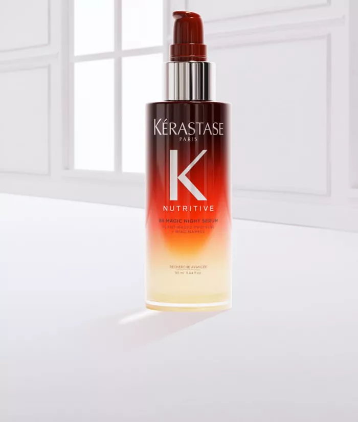 Eine Flasche Haarpflegeprodukt von Kerastase mit einem Gradient-Design, umgeben von einem Tropfen des Produkts auf einem hellen Hintergrund.