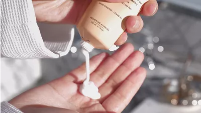 Hand halt einen Topf Tagescreme zur Pflege und zum Schutz von lockigem Haar