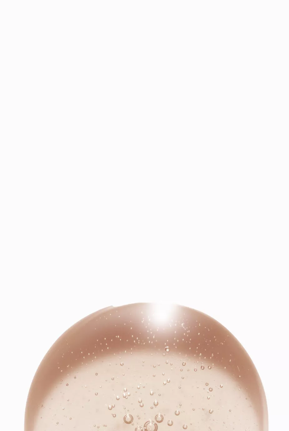 Ein zarter, transparenter Gel- oder Flussigkeitstropfen mit kleinen Blasen auf einem hellen Hintergrund.