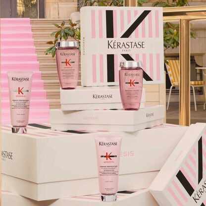 Kerastase-Produkte der Serie Genesis sind stilvoll auf gestapelten Verpackungen prasentiert. Eleganter Hintergrund.