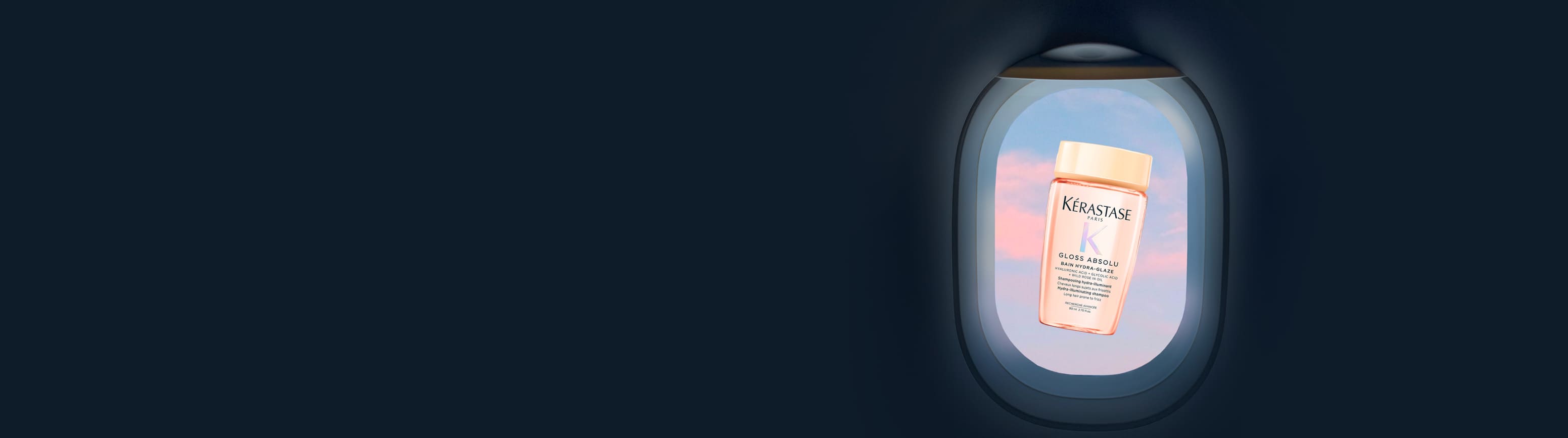 Transluzente, rosafarbene Reiseflasche von Kérastase Gloss Absolu Bain Hydra-Glaze, schwebend im Zentrum eines Flugzeugfensters, mit pastellfarbenem rosa und blauem Himmel.​