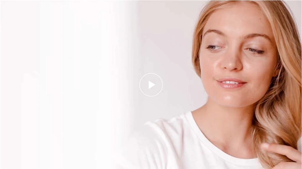 Junge Frau mit langen, blonden Haaren lächelt sanft und schaut nachdenklich zur Seite. Helle, freundliche Atmosphäre.