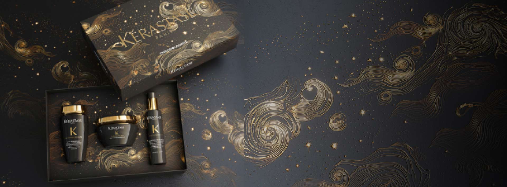 Luxuriöses Kerastase Pflege-Set in dekorativer Verpackung auf einem kunstvollen, goldenen Hintergrund.
