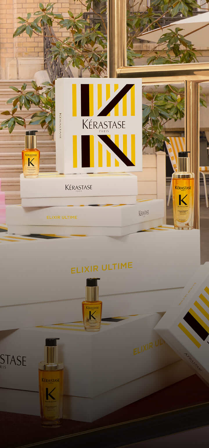 Helle Kérastase-Produkte auf weißem Untergrund; verpackt in elegantem Design mit goldenen Akzenten.
