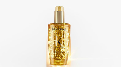 Flasche mit glänndem Haaröl von Kérastase, auf weißem Hintergrund, elegant und luxuriös.