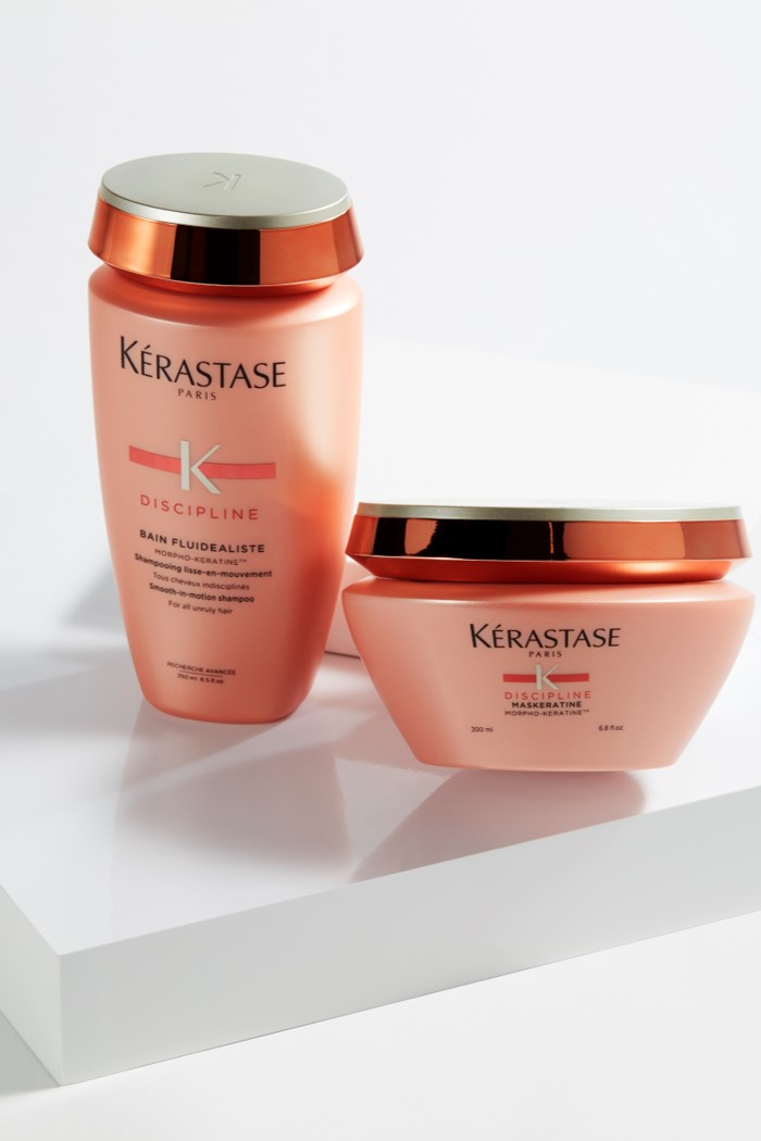Zwei Kérastase Produkte: Shampoo und Haarmaske in rosa Verpackungen auf einem weißen Untergrund.